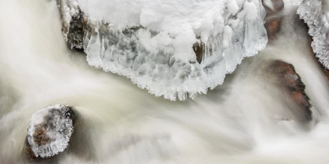 Langzeitbelichtung eines teilweise überfrorenen Flusslaufs