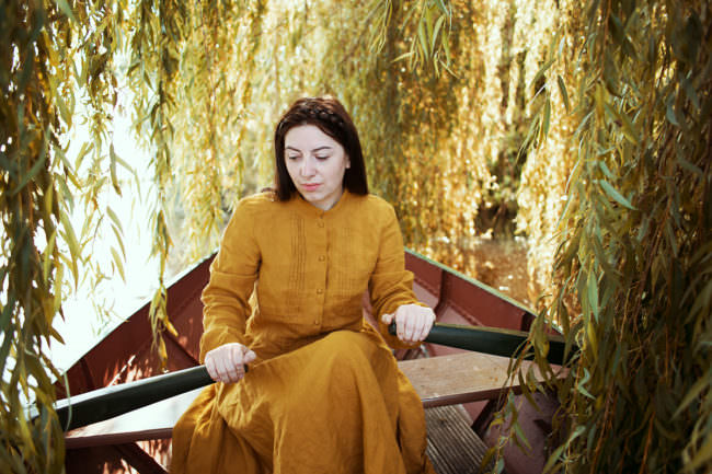 Frau im Ruderboot unter einer Weide