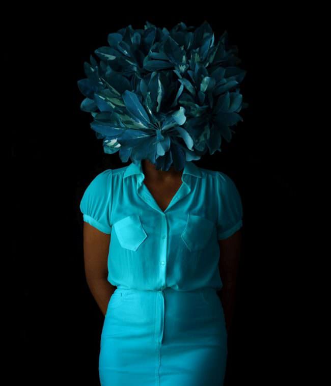 Frau mit blauen Blättern vorm Gesicht