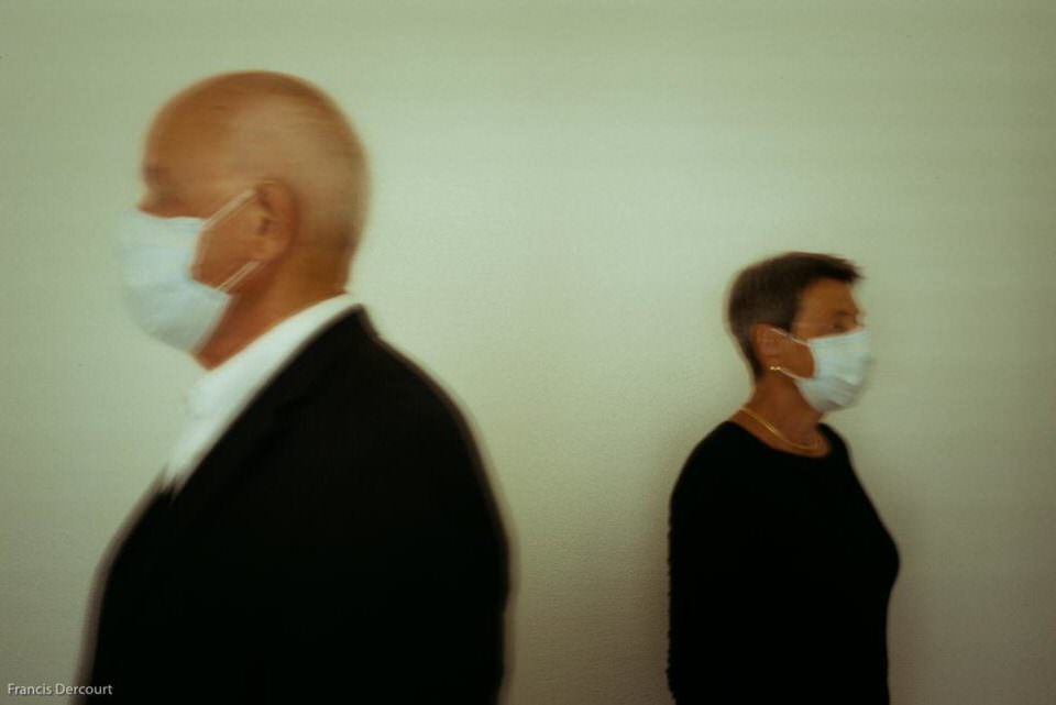 Zwei Menschen mit Masken schauen in verschiedene Richtungen