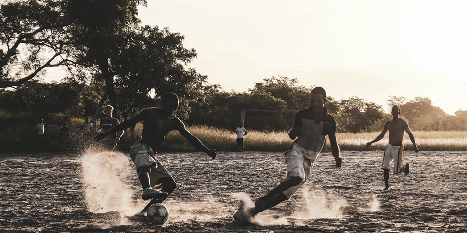 Jugendliche spielen Fußball auf sandigem Boden