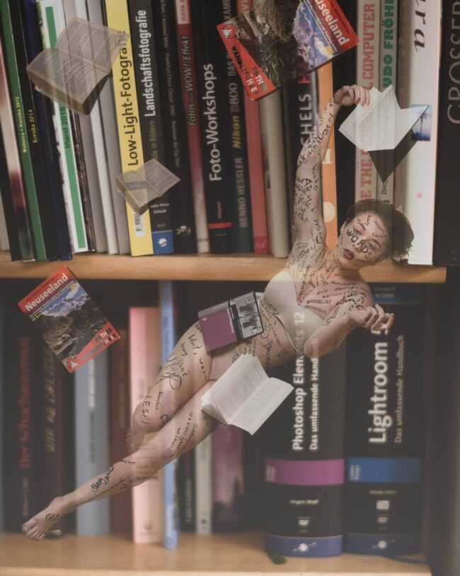 Surreales Bild einer Frau, die klein vor einem Bücherregal schwebt. Andere Bücher fliegen um sie herum.