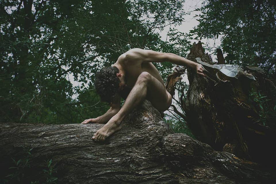 Ein nackter Mensch auf einem Baumstamm