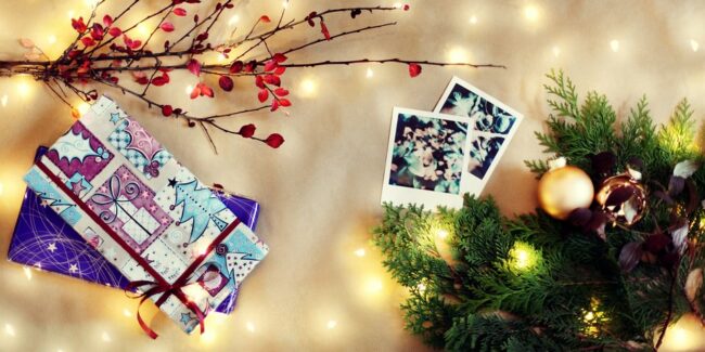 weihnachtliches Flatlay mit Pflanzen, Geschenken und Polaroids