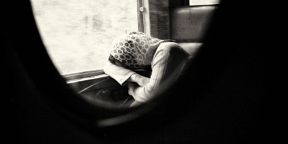 Schlafende Person im Zug mit Tuch bedeckt