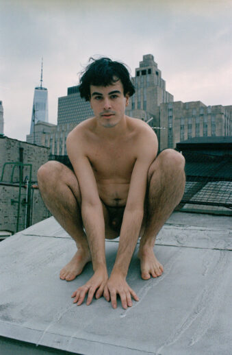 Eine Person hockt nackt auf einem Dach