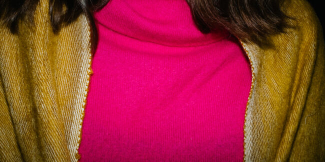 Oberkörper in pinkem Pullover mit goldenem Tuch