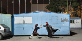 Zwei Frauen tanzen vor einem kleinen Häuschen