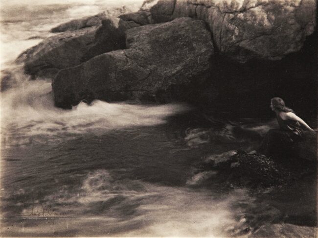 Frau im Wasser vor Felsen