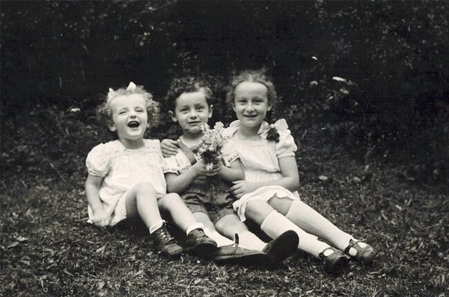 drei Kinder sitzen auf einer Wiese