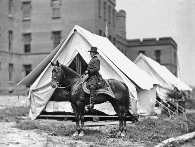 Soldat auf Pferd vor Zelten und Gebäuden