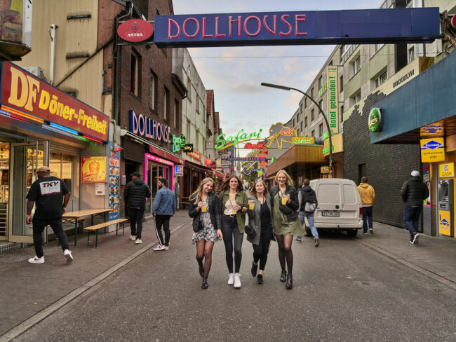 Menschen posieren unter dem Schild "Dollhouse"