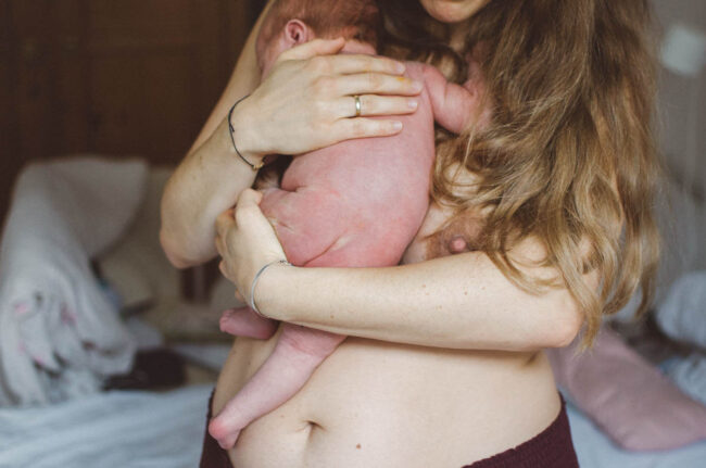 Neugeborenes wird von Frau gehalten