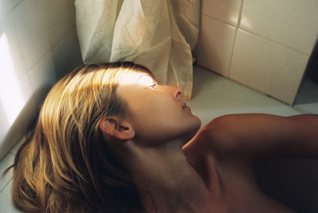Portrait einer Frau am Rand einer Badewanne liegend