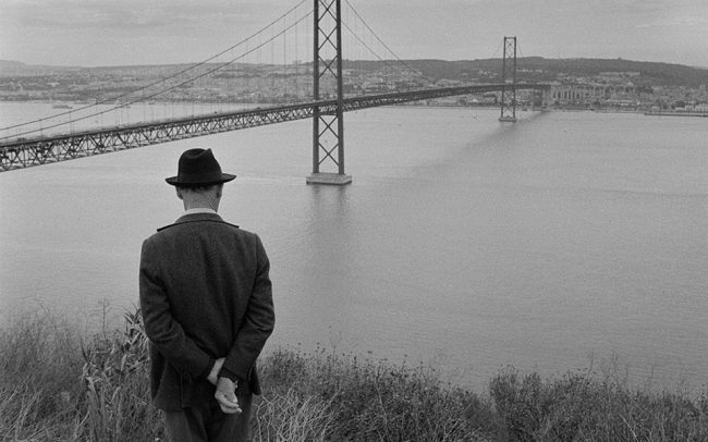 Mann mit Hut sieht auf eine Brücke