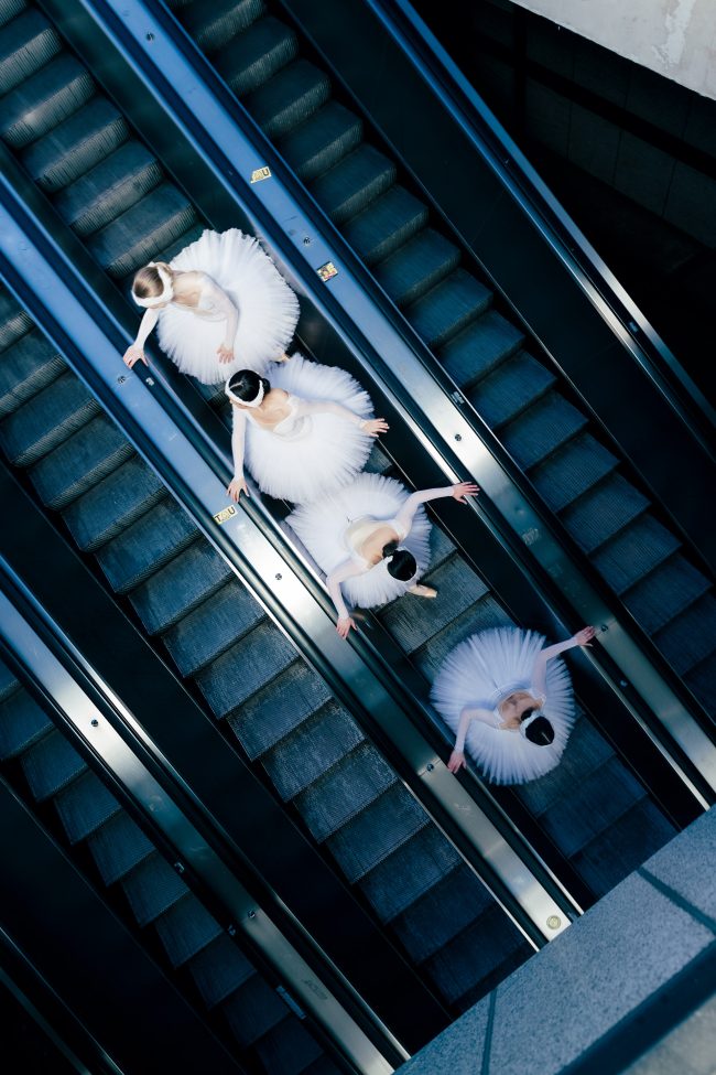 Ballerinas auf einer Rolltreppe von oben fotografiert