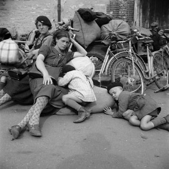 Frauen und Kinder rasten auf Gepäck neben Fahrrädern.